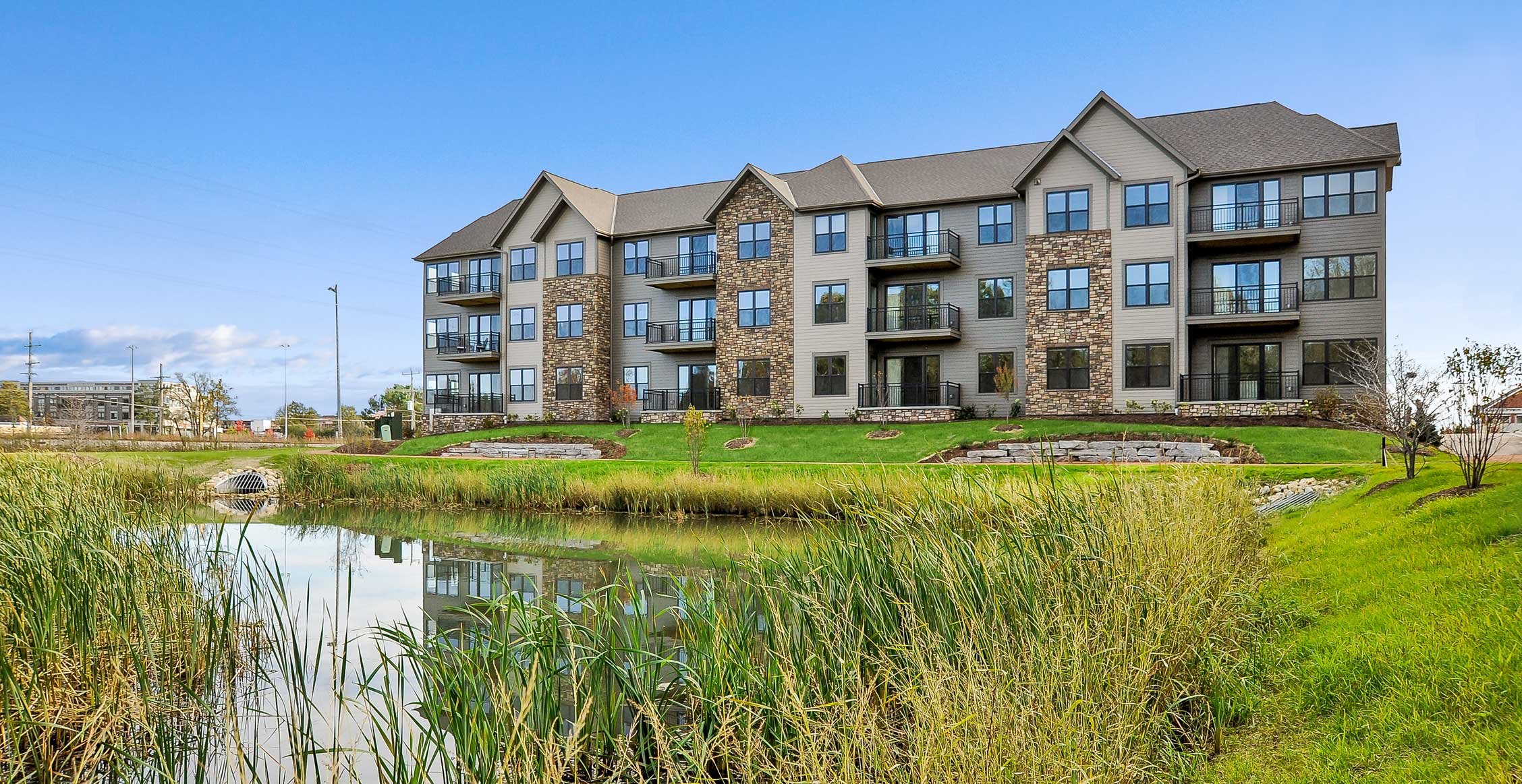 Spur 16 residential building viewed across a pond and landscaped green space in Mequon, Wisconsin.