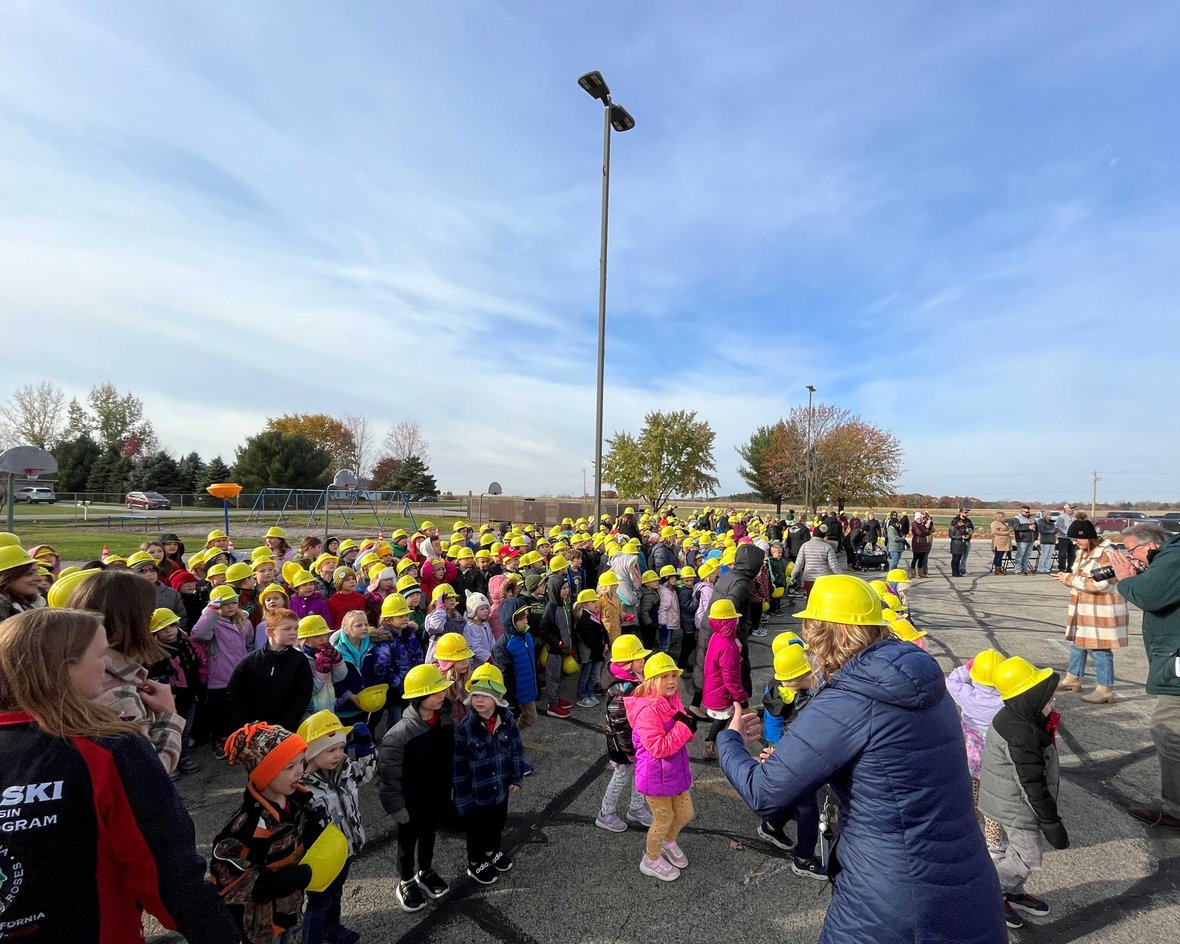 Students gather on playground in CD Smith Construction hard hats at Pulaski School District Sunnyside Project Groundbreaking