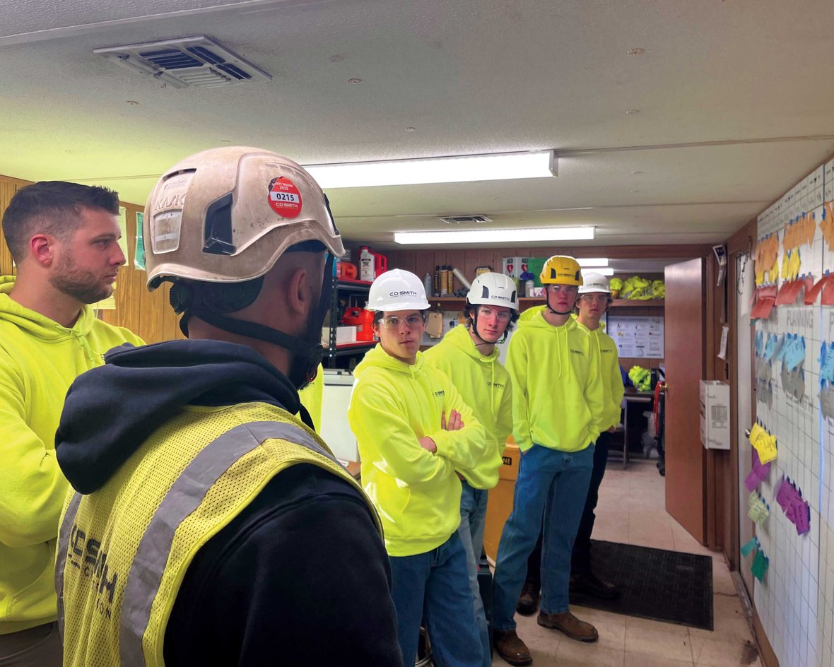 Students tour a C.D. Smith commercial construction jobsite trailer in Wisconsin, observing a pull planning schedule and learning about project management and skilled trades careers.