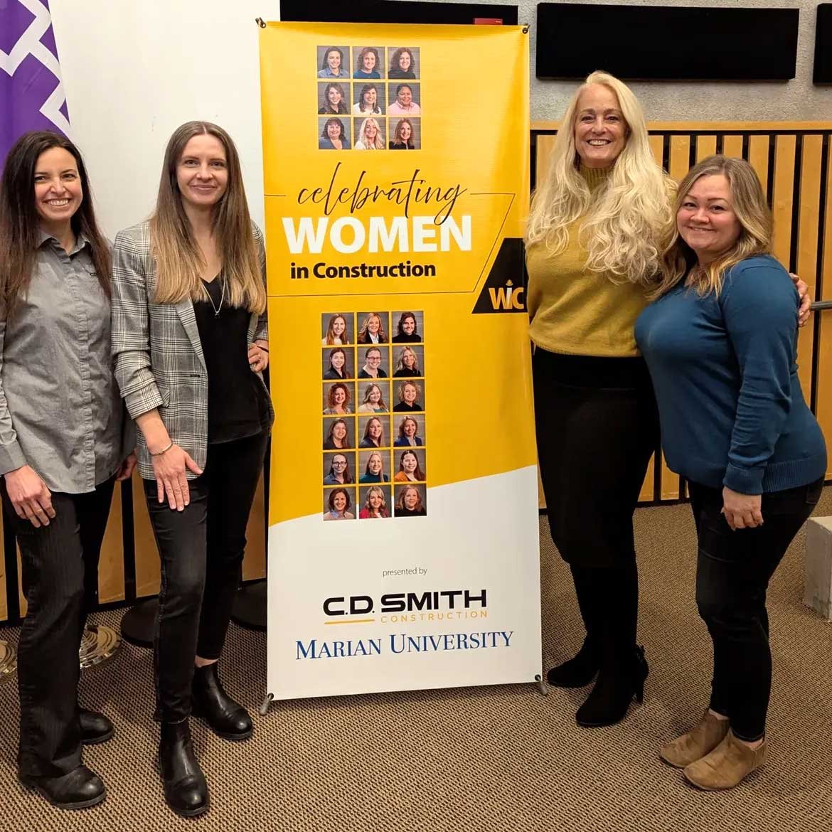 CD SMith team and Ana from Xena Workwear pose by banner at Women in Construction 2025 event hosted by Marian University and CD Smith
