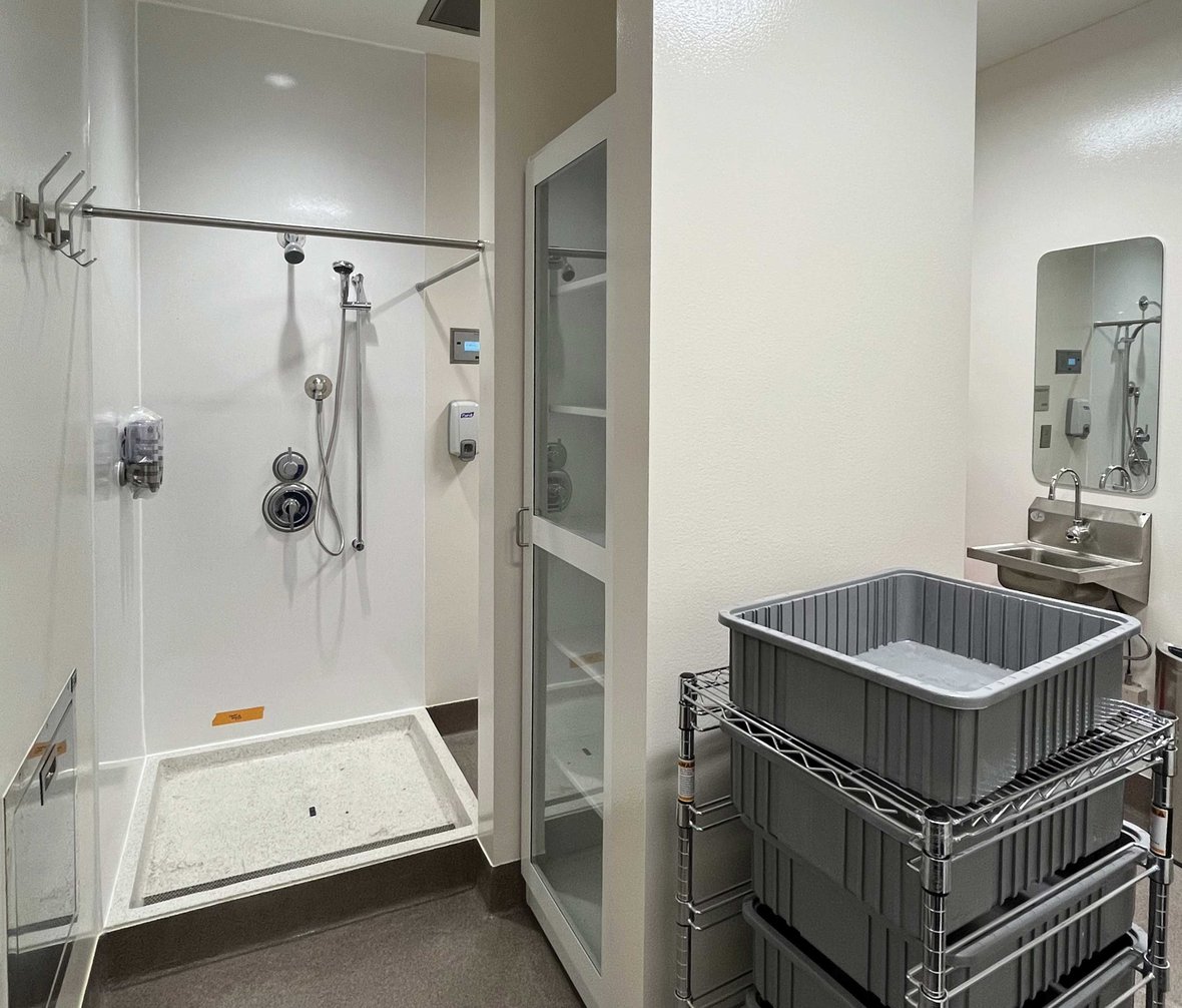 BSL-3 anteroom with shower pass-through storage sink and cleanable surfaces supporting controlled entry and containment protocols