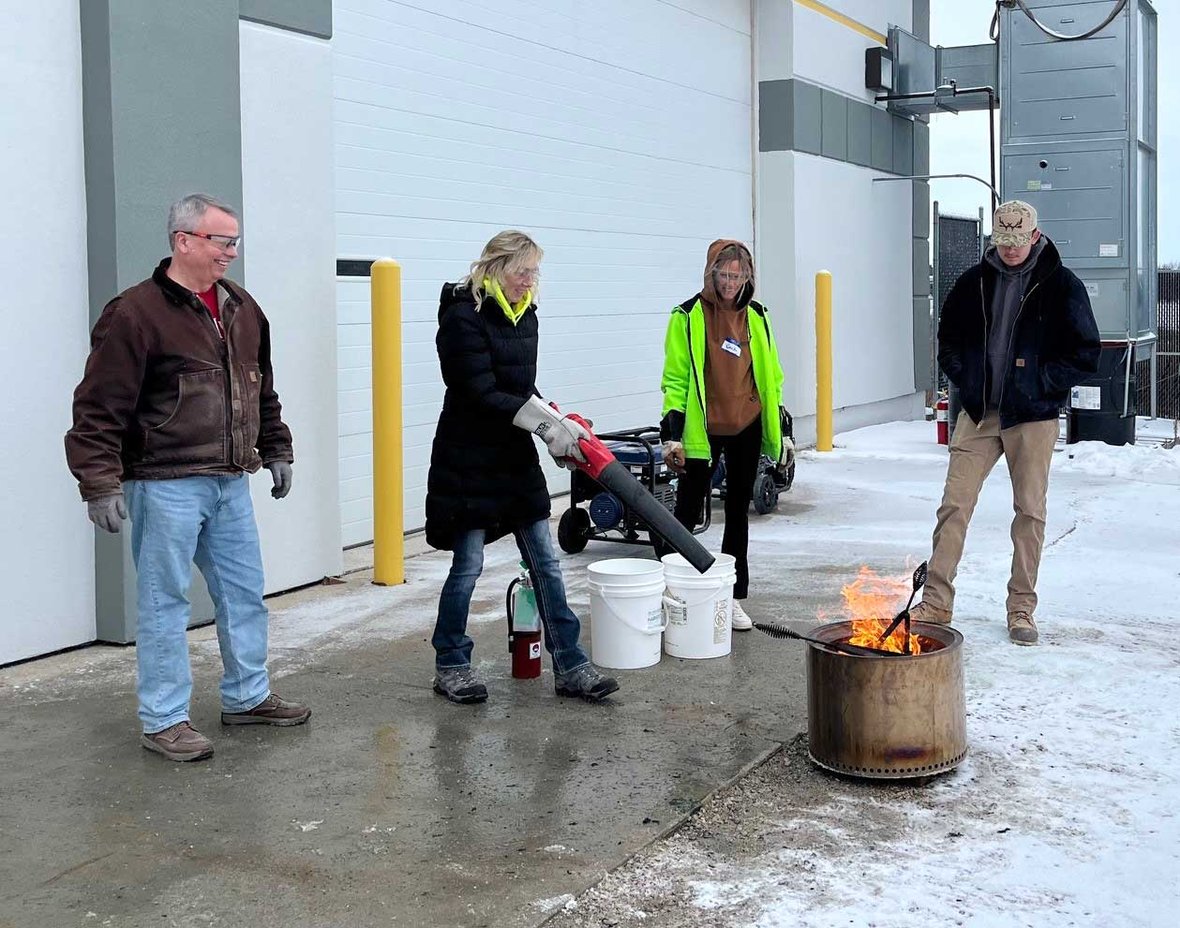 Volunteers branding wooden bed frames over a fire barrel during Sleep in Heavenly Peace bed build