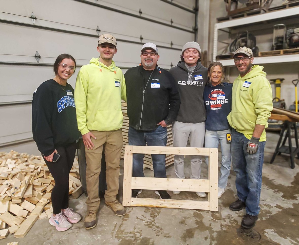 C.D. Smith Construction employees and community volunteers with completed bed frames during Sleep in Heavenly Peace bed build