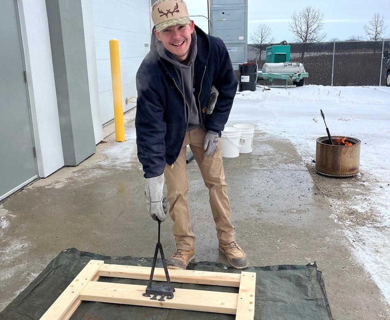 CD Smith Youth Apprentice and volunteer branding wooden bed frame during Sleep in Heavenly Peace bed build