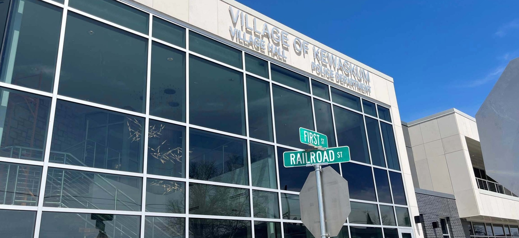Exterior of the new Village of Kewaskum Government and Community Center in Wisconsin, with Village Hall and Police Department signage and street signs for First Street and Railroad Street. Built by C.D. Smith Construction.