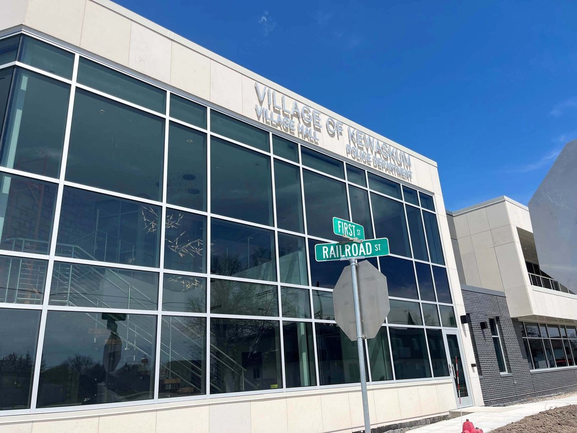 Exterior of the new Village of Kewaskum Government and Community Center in Wisconsin, with Village Hall and Police Department signage and street signs for First Street and Railroad Street. Built by C.D. Smith Construction.