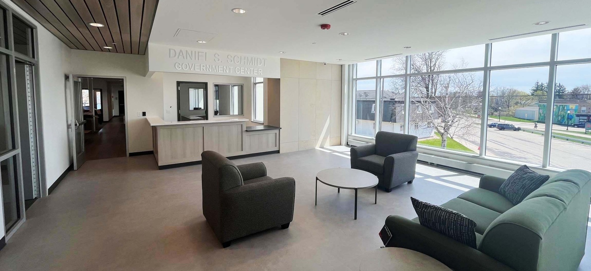 Lobby of the Daniel S. Schmidt Government Center in Kewaskum, Wisconsin, with modern reception desk, seating area, and large windows providing natural light. Built by C.D. Smith Construction.