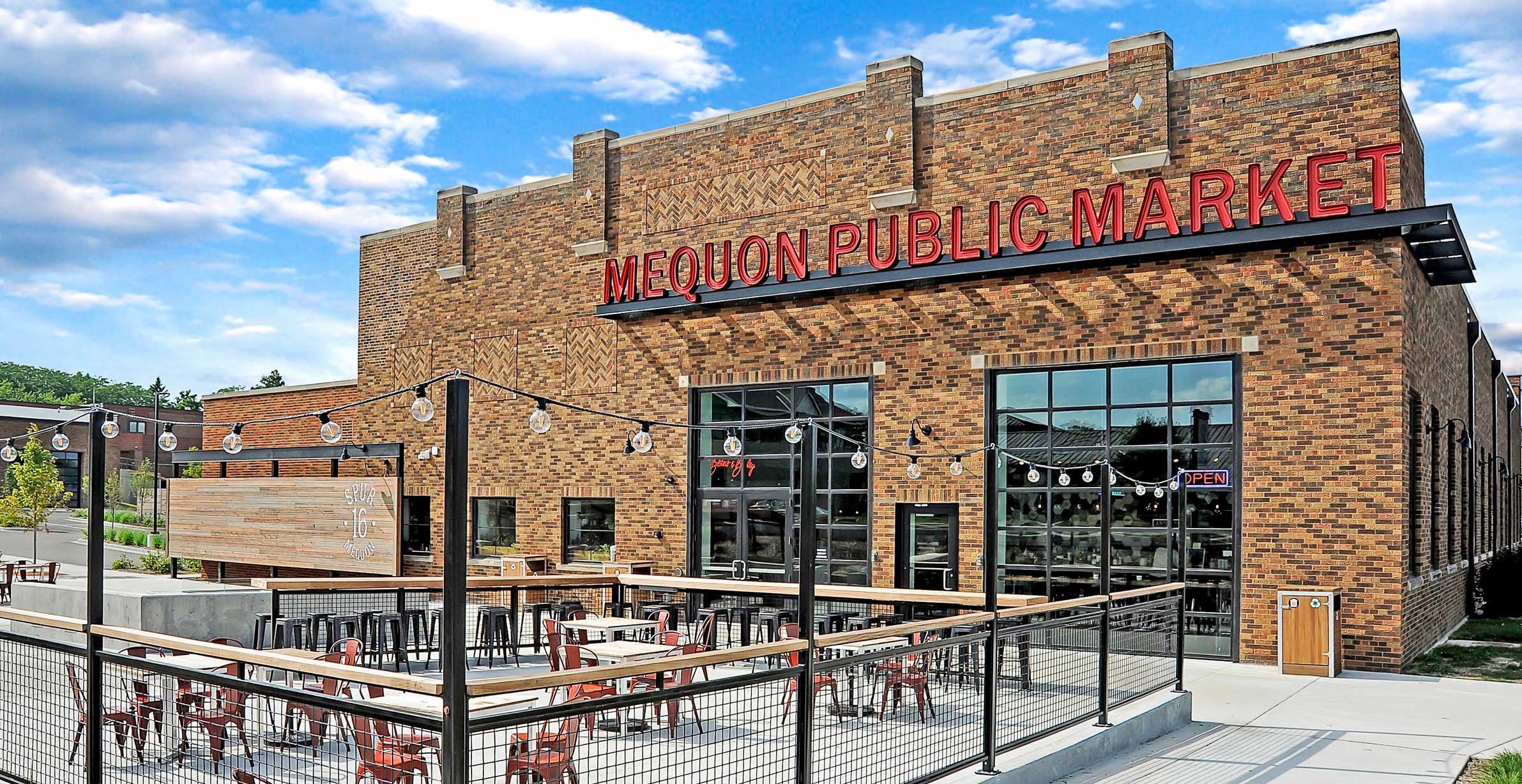 Mequon Public Market at Spur 16 in Mequon, Wisconsin, featuring brick exterior, outdoor patio seating and market entrance.