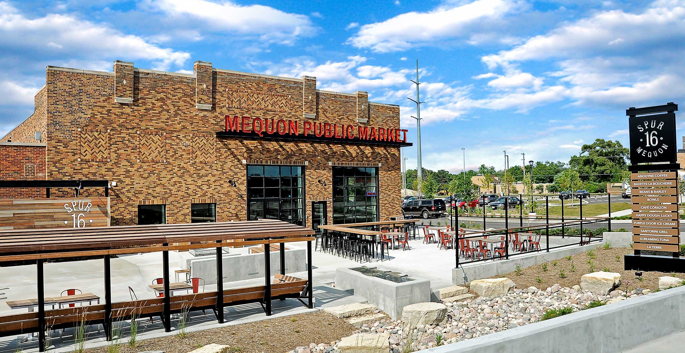 Exterior view of Mequon Public Market at Spur 16 with outdoor dining terrace and tenant directory signage in Mequon, Wisconsin.
