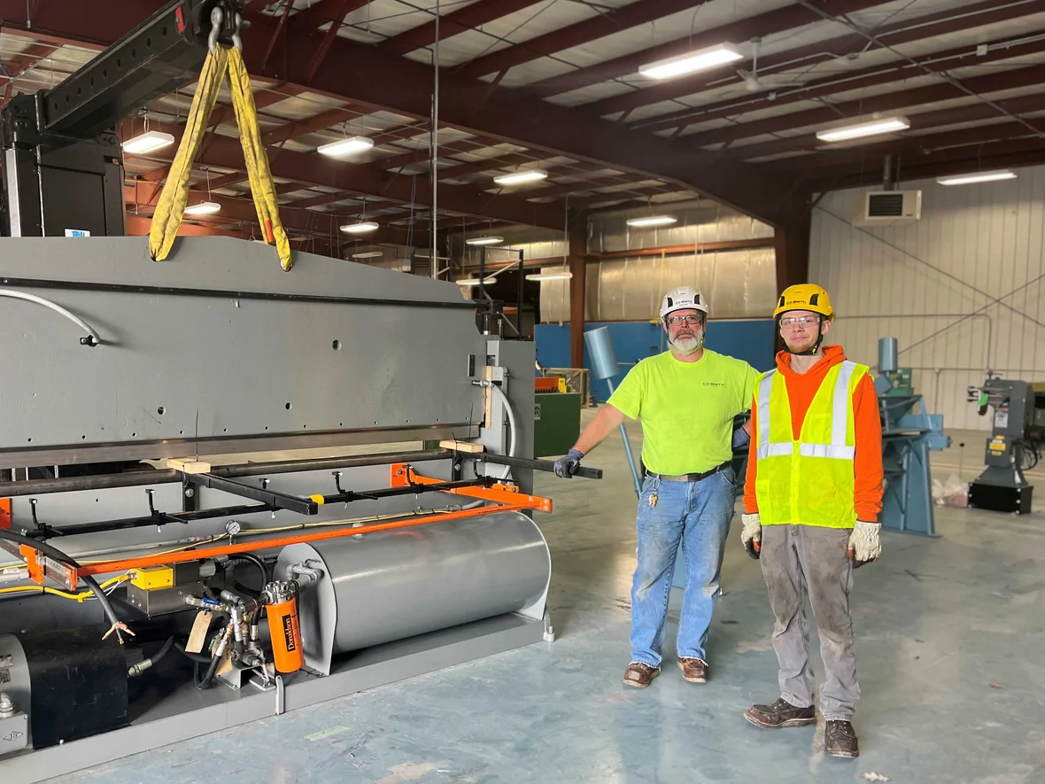 Millwright crew standing beside the successfully installed shearing machine after safe and efficient relocation.