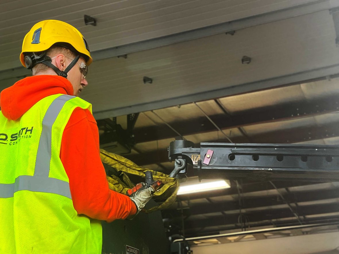 Millwright using hand signals to guide a forklift operator during the precise positioning of industrial equipment.