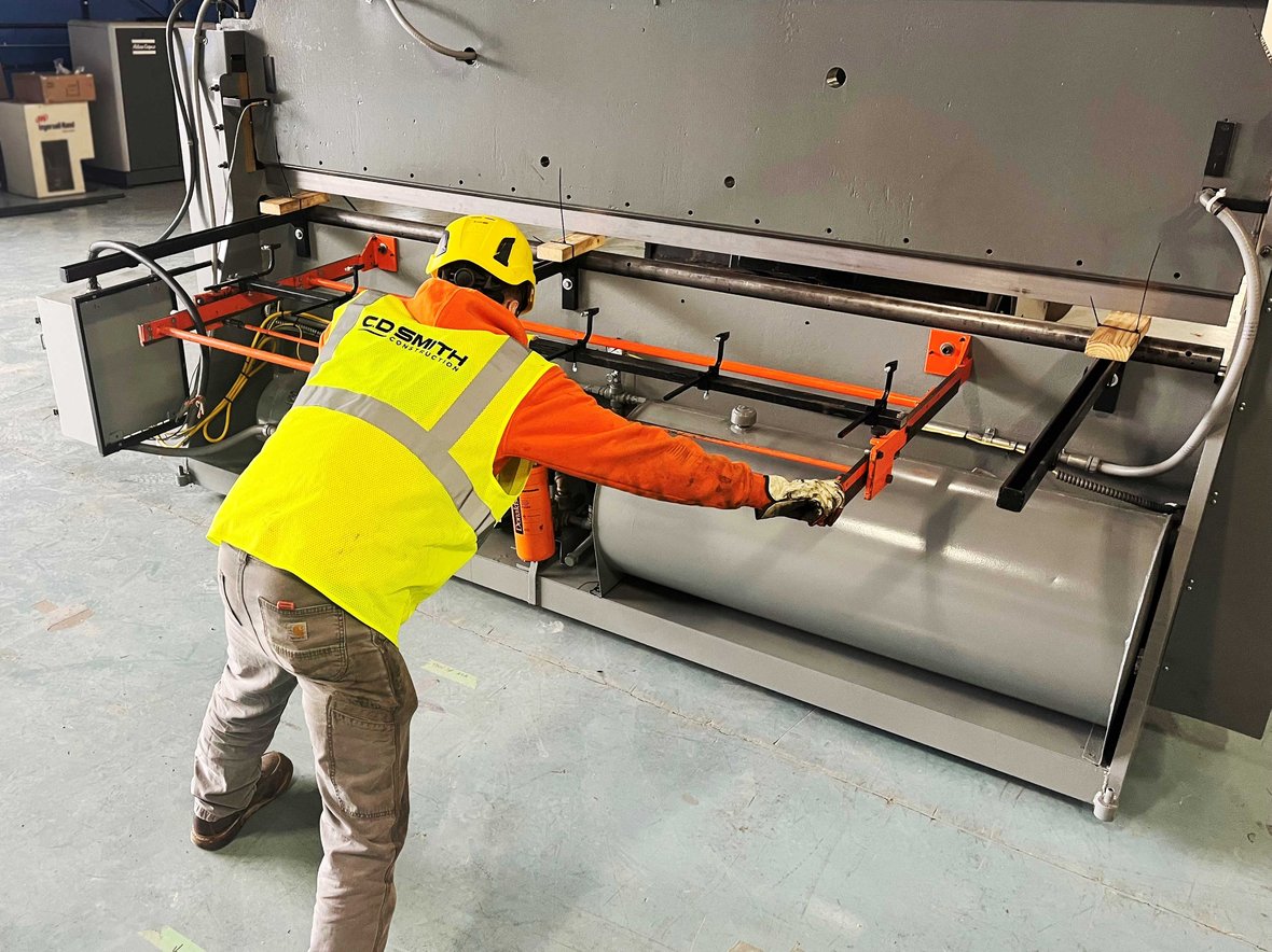 Millwright inspecting and aligning a shearing machine before relocation to ensure safe and precise equipment movement.