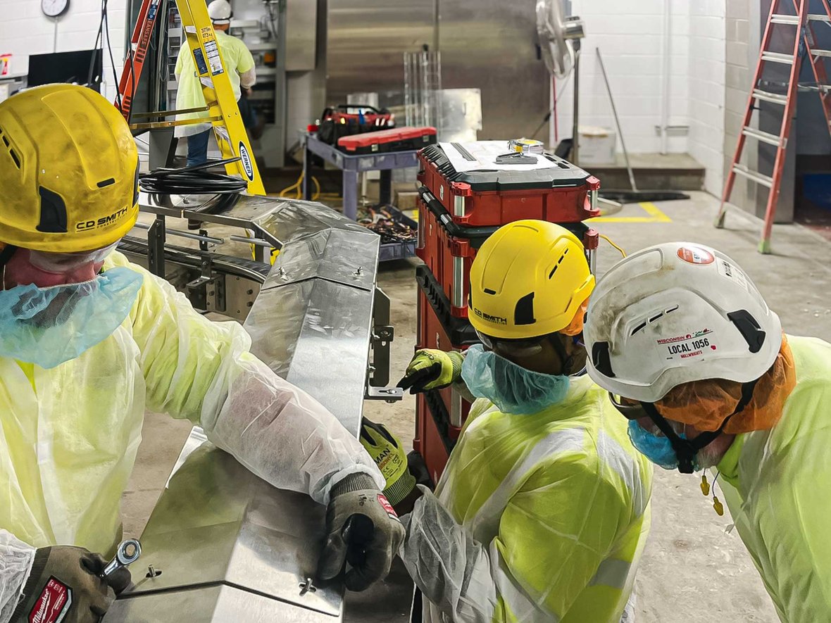 Millwright team aligning and installing an industrial conveyor system inside a manufacturing facility