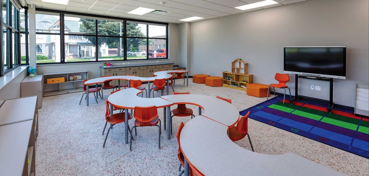Licensed childcare classroom at the Ripon Boys & Girls Club with collaborative tables learning rug and large exterior windows
