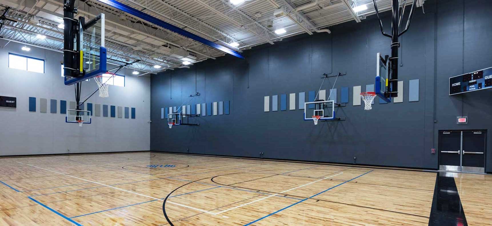 Full-size gymnasium at Boys & Girls Club of the Tri-County Area with hardwood court basketball hoops and acoustic wall panels