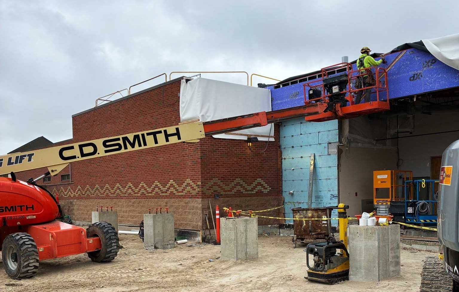 C.D. Smith crew member working from an aerial lift with concrete canopy piers in the foreground at the SSM Health Cancer Care expansion site in Fond du Lac.