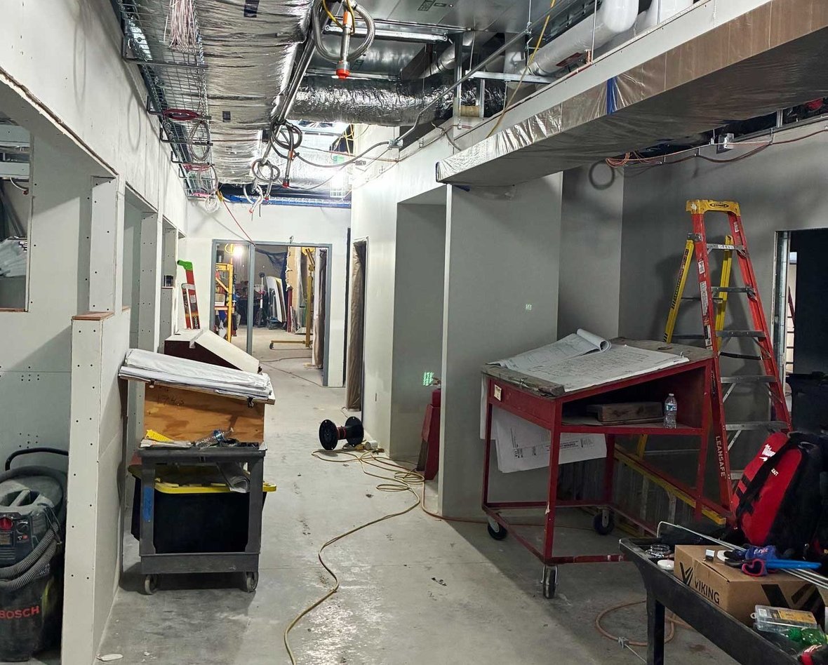 Interior corridor with drywall nearing completion and mechanical electrical and plumbing systems overhead at the SSM Health Cancer Care expansion in Fond du Lac.