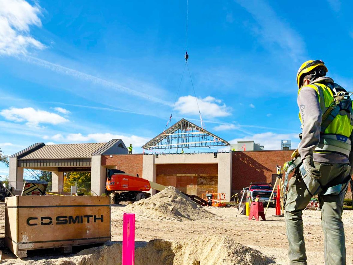 A construction team member observing a crane lifting structural components into place at the SSM Health Cancer Center expansion site.