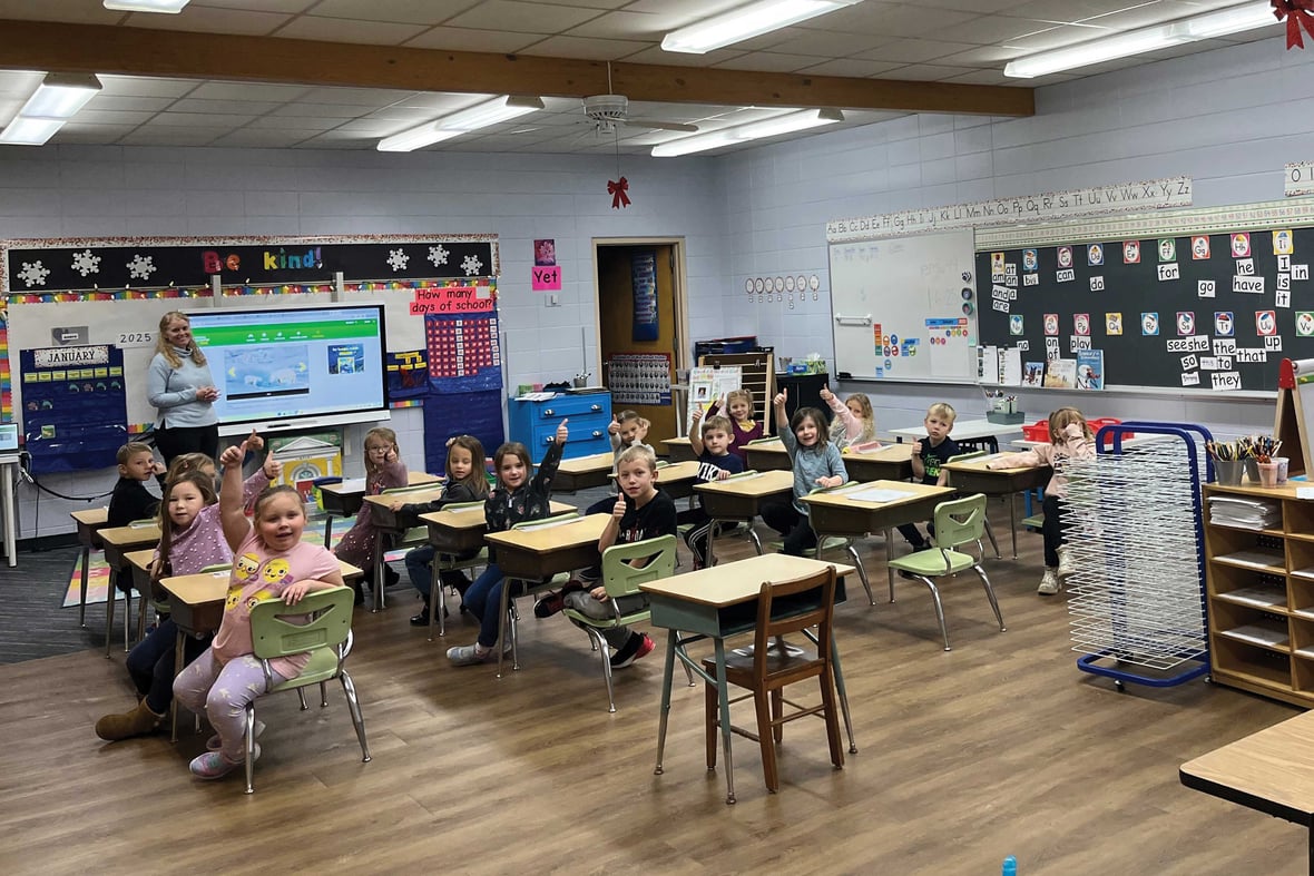 Elementary classroom with students seated at desks, interactive board, and wall displays