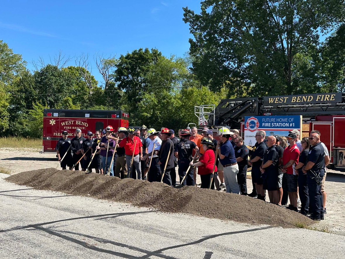 City officials and firefighters lifting the first shovels of soil together to mark the start of construction for West Bend Fire Station 1