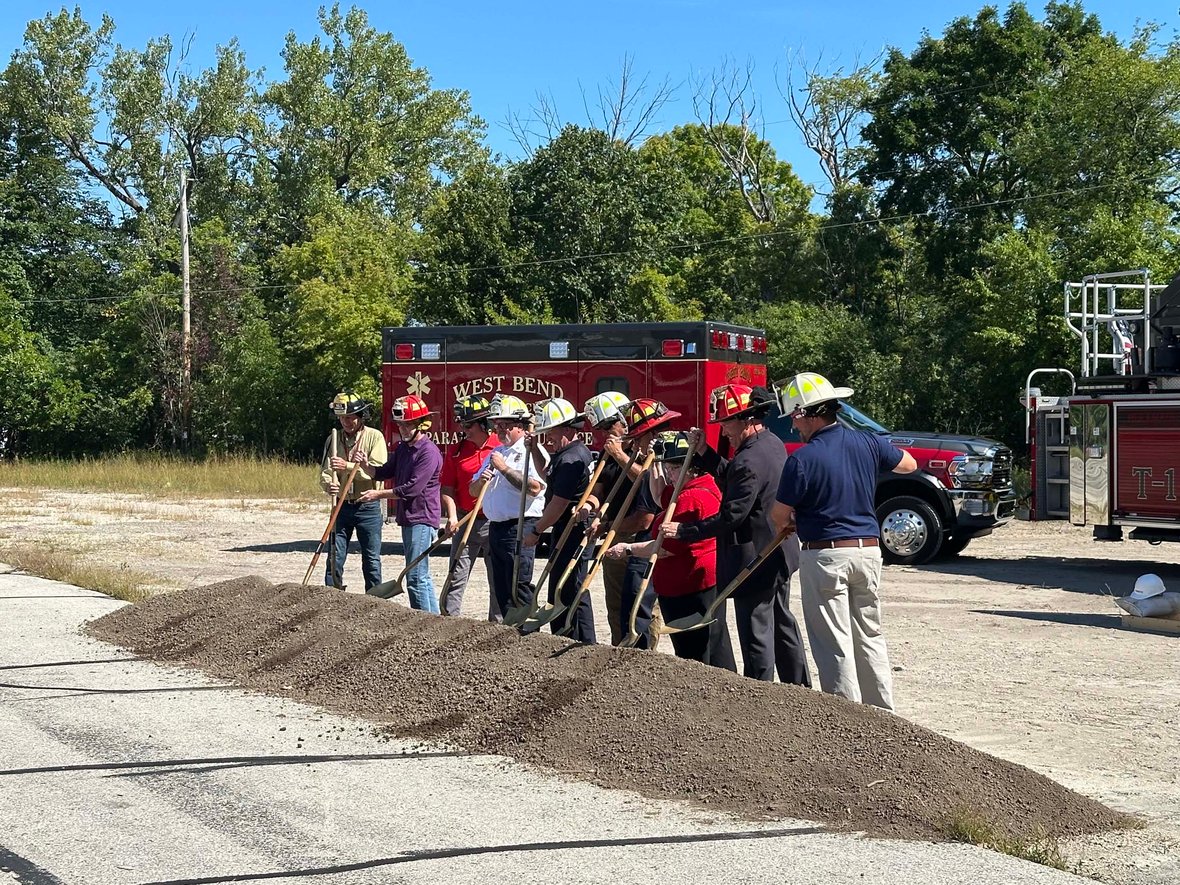 Participants in helmets posed with shovels along the dirt mound at the Fire Station 1 groundbreaking