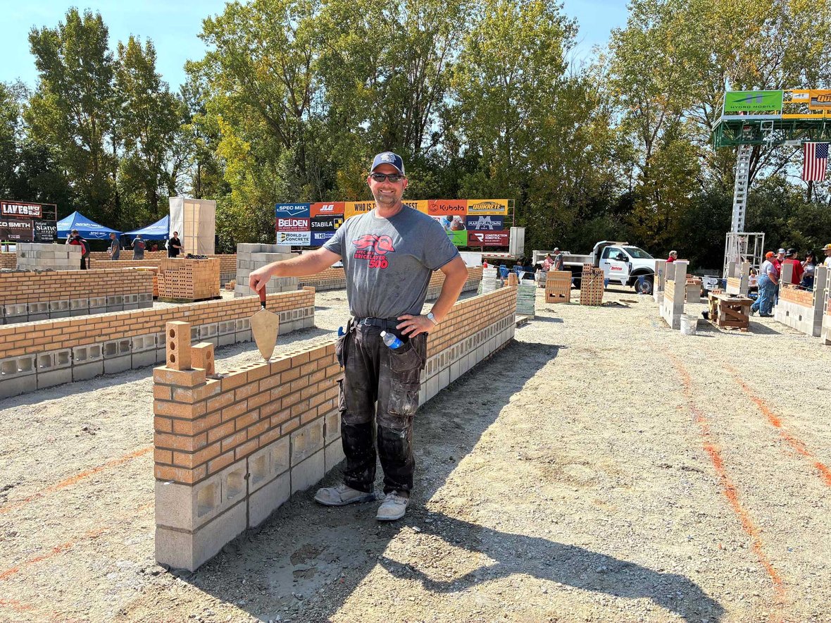 Mason stands beside partially built brick wall during the 2025 Spec Mix Bricklayer 500 competition in Fond du Lac.